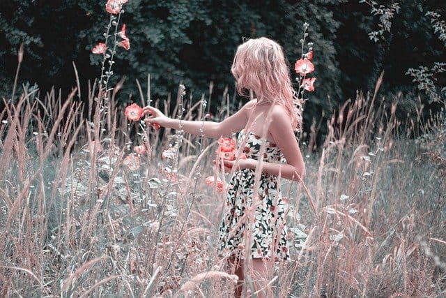 Девушка в летнем платье в поле с луговыми цветами